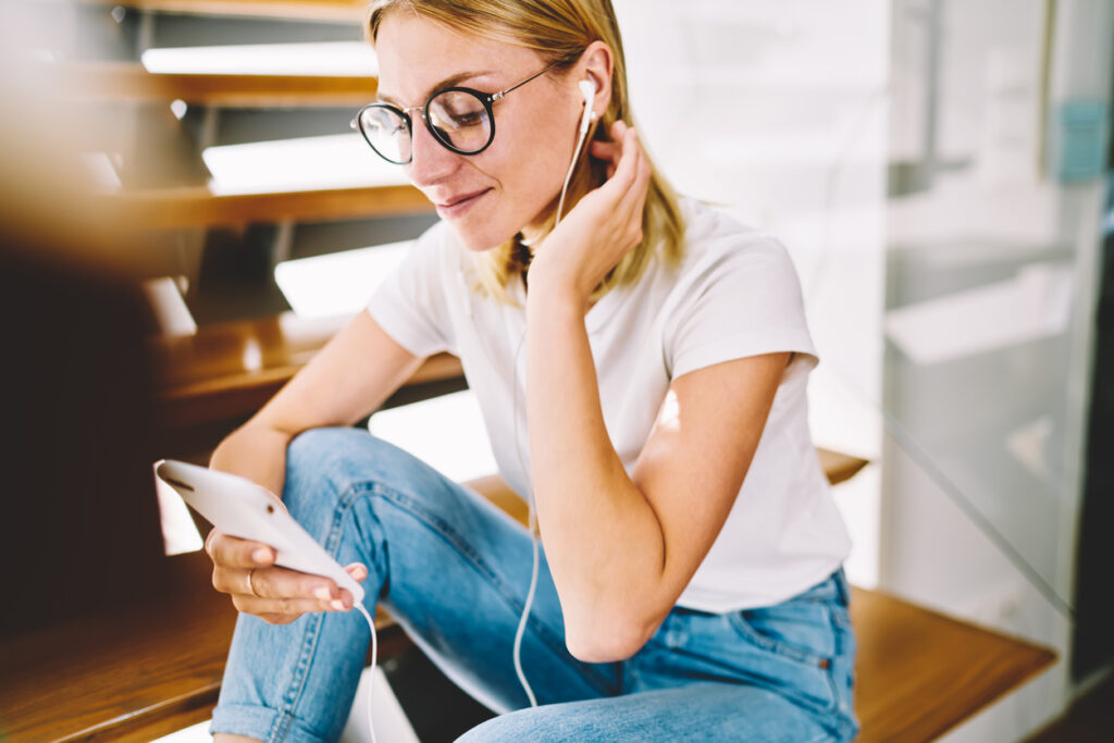 ragazza bionda che ascolta un podcast sulle scale
