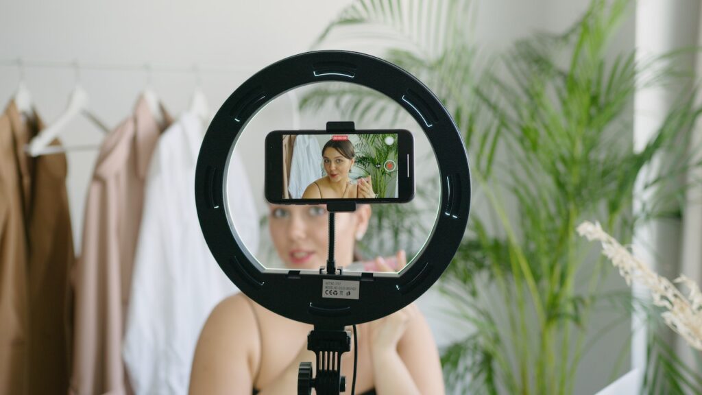 Una influencer sta registrando una live col telefono e una ring light