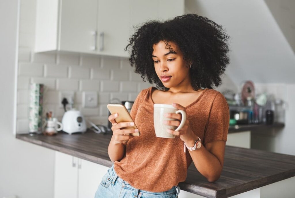 ragazza che beve il caffè e guarda il cellulare