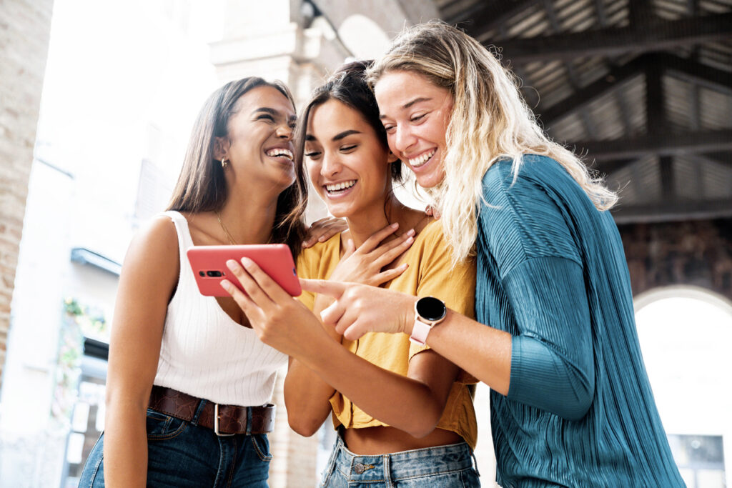 tre amiche al telefono che ridono
