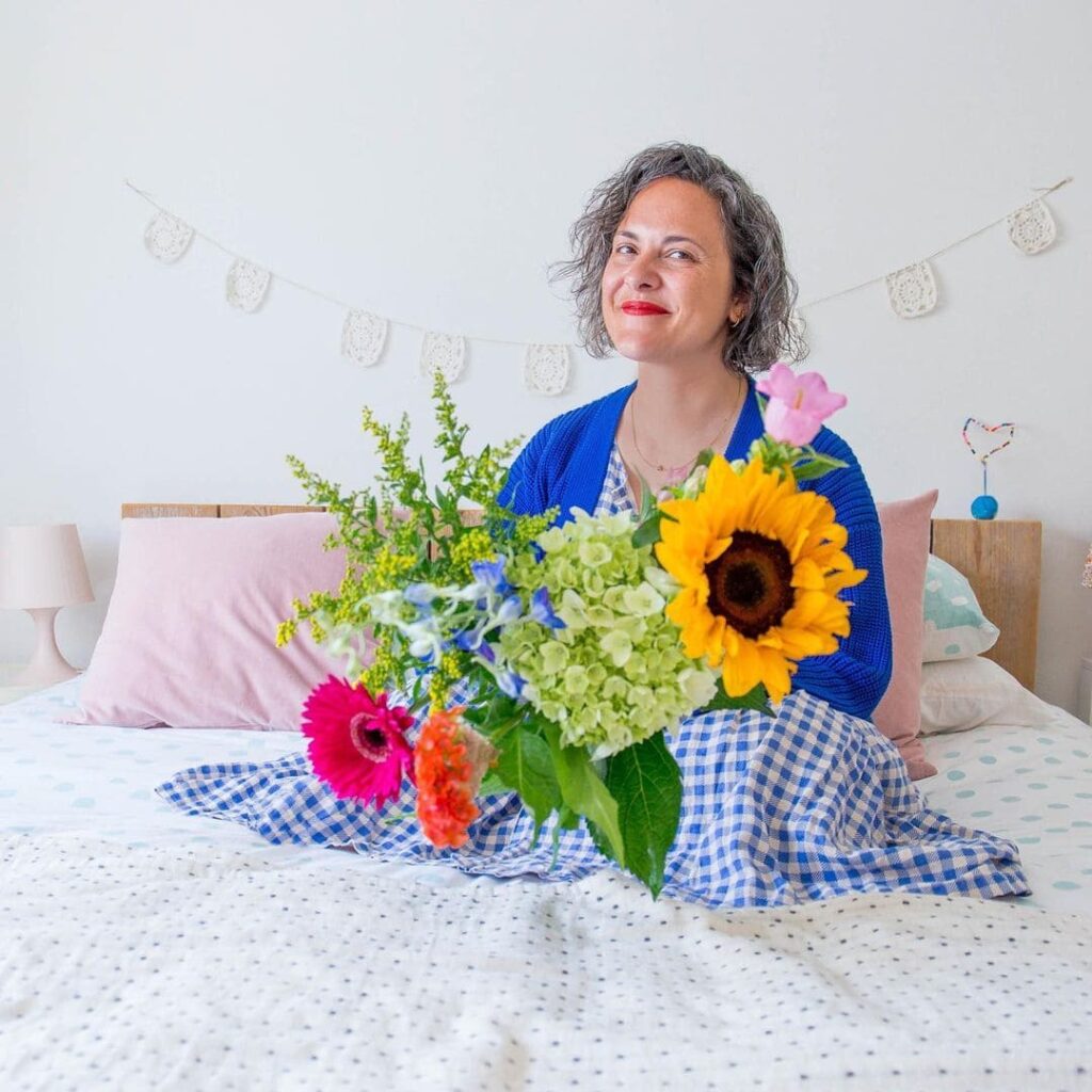 Ilaria Chiaratti seduta sul letto con un mazzo di fiori