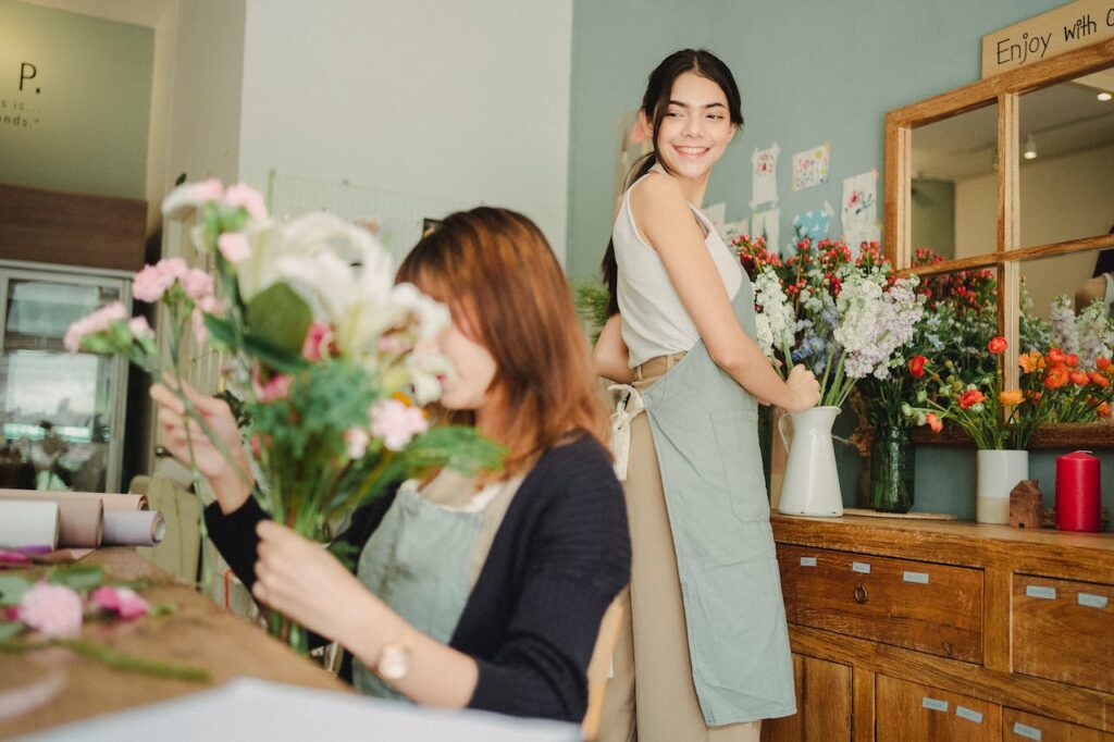 Due ragazze in un fioraio che preparano un mazzo di fiori